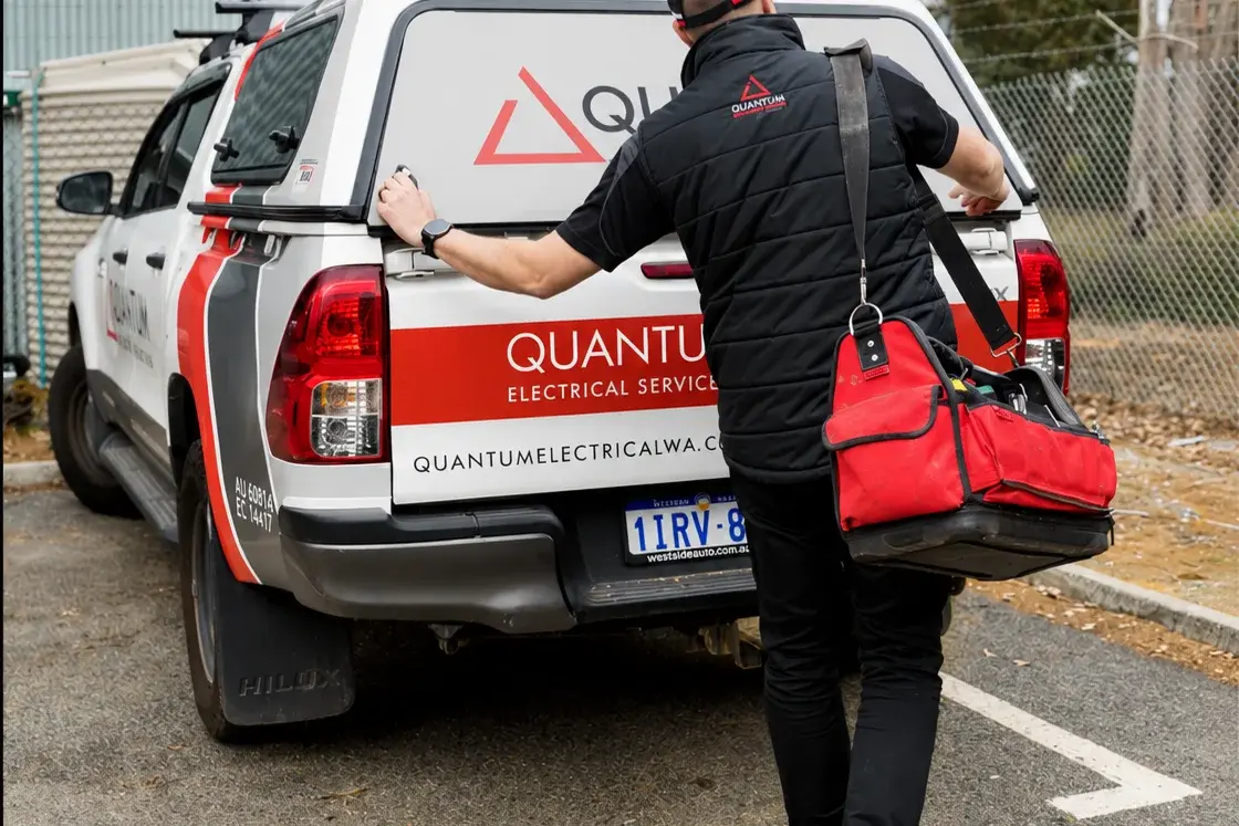 Quantum electrician in a branded work shirt working under the eaves of a Perth Hills home
